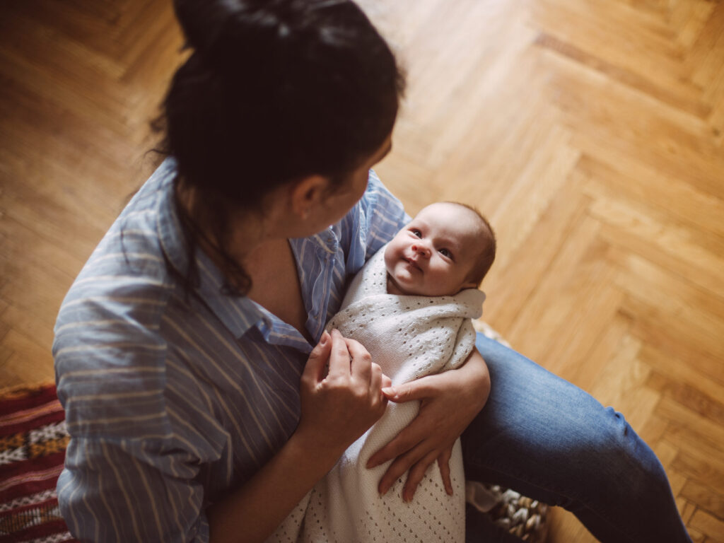 A mother holding her baby at home, representing CHAMP's breastfeeding and maternal mental health research