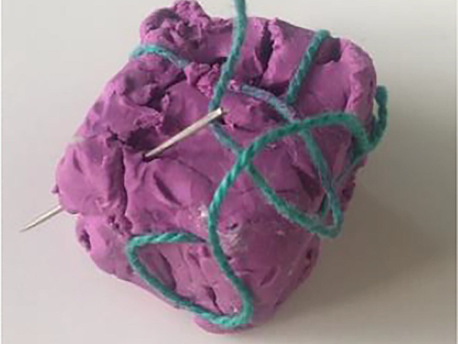 An abstract sculpture of tangled thread and needles through clay, symbolising the physical and emotional impact of endometriosis